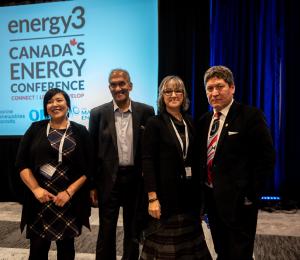 Four individuals standing in front of a conference stage.