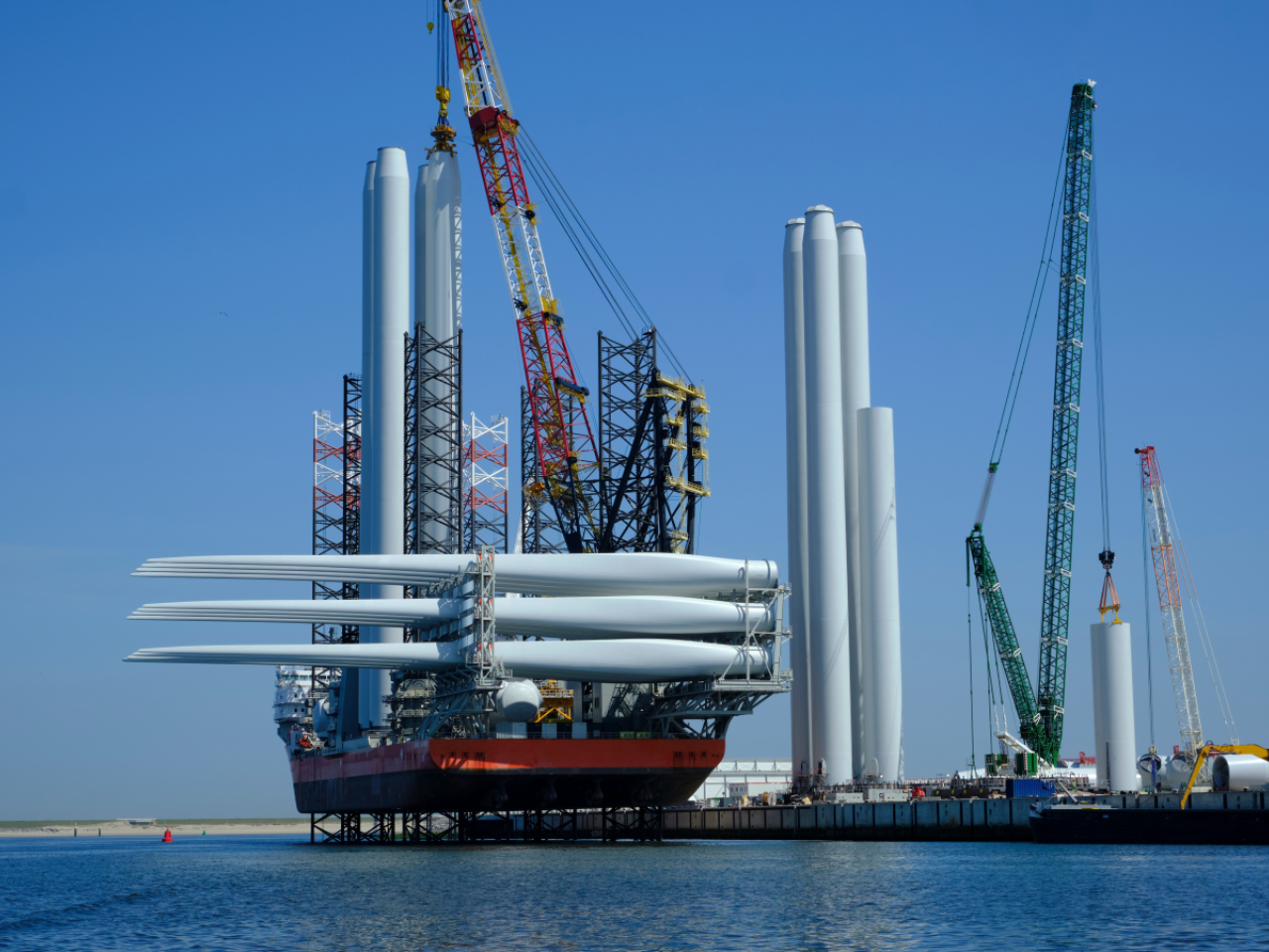 Ship carrying wind turbine parts is docked at a port.