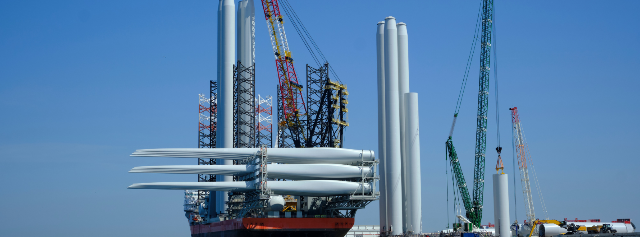 A ship carrying wind turbine ports is docked at a port