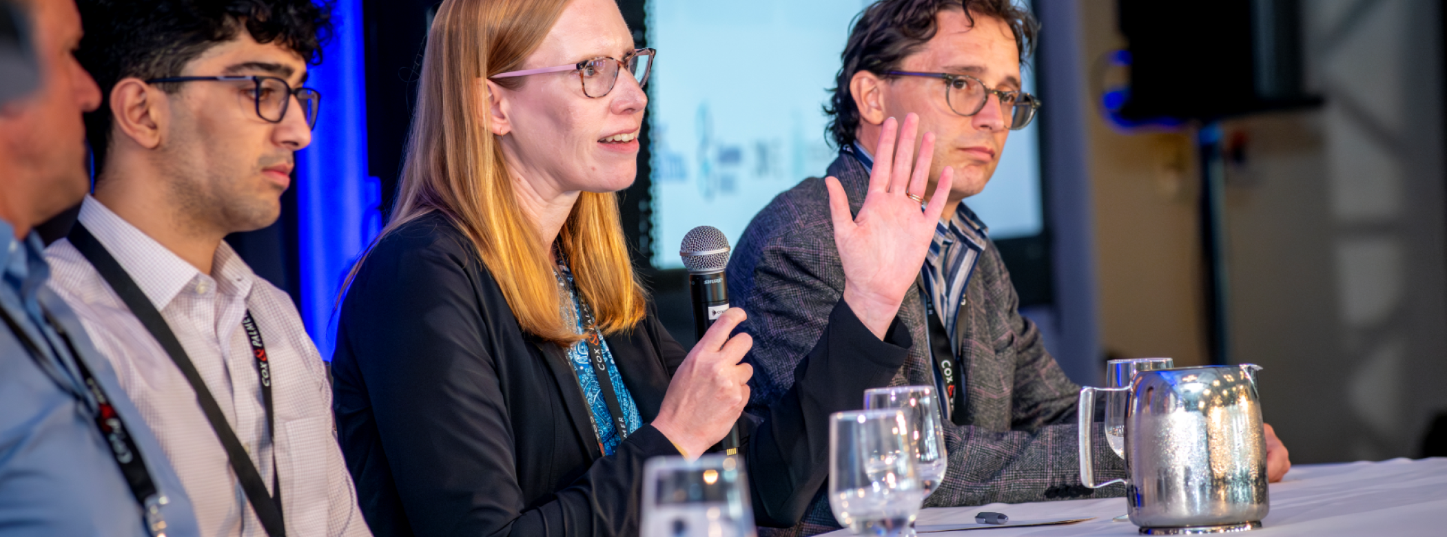 Four panelists are seated after their presentations and one is answering questions
